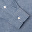 A blue work shirt sleeve and cuff, two white buttons.