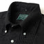 A closeup of the black button down collar, with white buttons and a green tag.